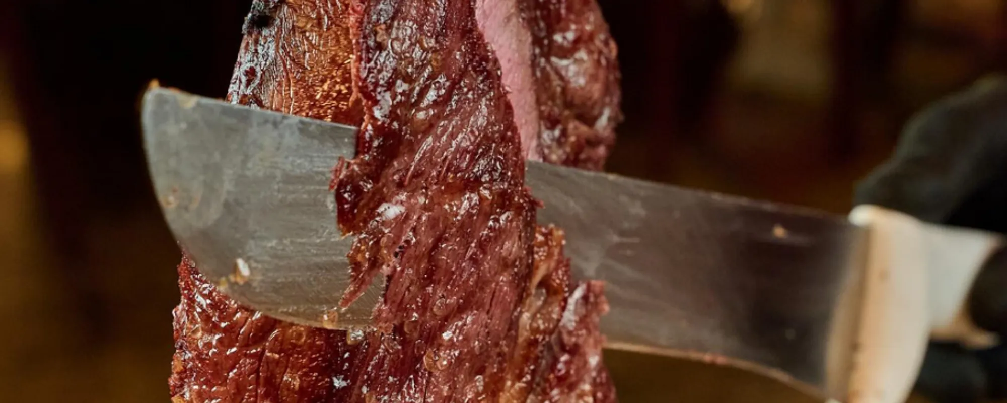 Corte de picanha sendo fatiado na faca, ainda no ponto, no salão do Steak Bull.